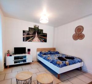 a bedroom with a bed and two chairs and a tv at studio cosy & fun face aux château fléchettes in Gaillon