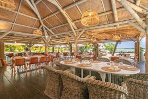 a restaurant with tables and chairs and a view of the ocean at Villa Les Agaves front de mer in Le François