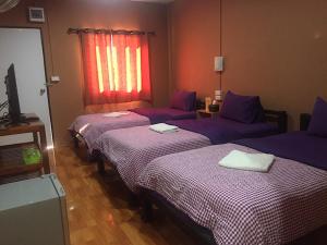 a room with three beds with purple sheets and a window at Panngernpanthong inn resort in Ban Nong Chaeng