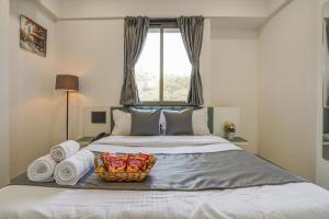 a bed with a basket of towels and a window at Hotel Zenora in Méribel Village