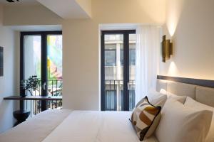 a bedroom with a white bed with a balcony at Bellén Athens Ηotel in Athens