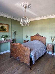 a bedroom with a large bed and a chandelier at L'auberge Beauraing in Baronville
