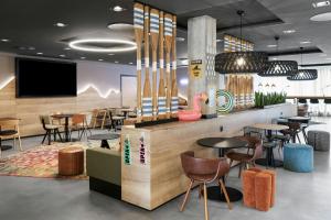 a restaurant with tables and chairs and a flat screen tv at Moxy Zurich in Zurich +95 photos