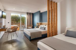 a hotel room with two beds and a balcony at Enorme Infinity Beach ex Infinity Blue in Hersonissos