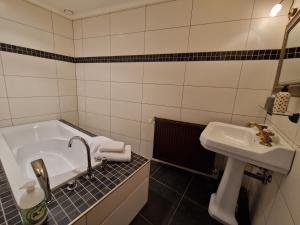 a bathroom with a tub and a sink at L'auberge Beauraing in Baronville
