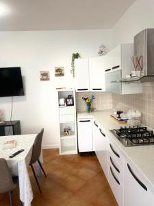 a kitchen with white cabinets and a table and a stove at Granaretto 27 in Palidoro
