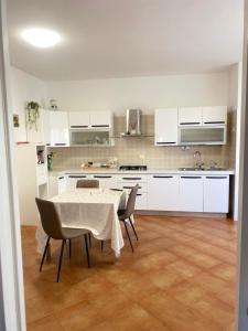 a kitchen with white cabinets and a table and chairs at Granaretto 27 in Palidoro