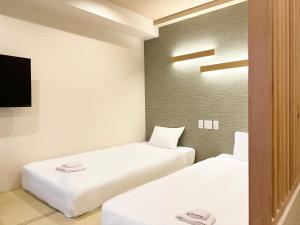 a room with two beds and a tv at Osaka Ebisu Hotel in Osaka
