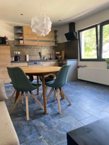 a kitchen with a wooden table and green chairs at Relaxen am Waldesrand Fewo 2 in Ahrbrück