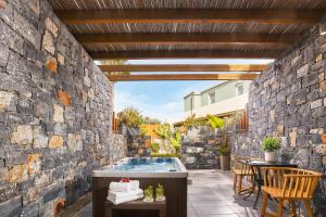 a patio with a stone wall and a hot tub at Enorme Infinity Beach ex Infinity Blue in Hersonissos