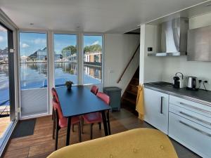 a kitchen with a table and chairs with a view of the water at Houseboat Robbedoes in Offingawier