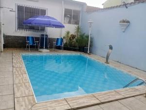a swimming pool with blue water in a house at CASA com ACOMODAÇÃO para 6 PESSOAS in Guaratinguetá