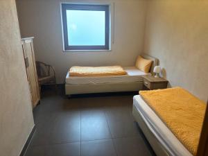 a small room with two beds and a window at Panoramaferienwohnungen Stemler in Eulenbis