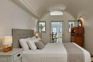 a bedroom with a large bed with white sheets and pillows at Iliovasilema Suites in Imerovigli +127 photos