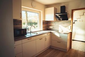 a kitchen with white cabinets and a sink and a window at Ferienhaus Ostsee in Rabenkirchen-Faulück
