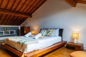 a bedroom with a large white bed with two lamps at Casa da Arvore Chale by Green Vacations in Calhetas +20 photos