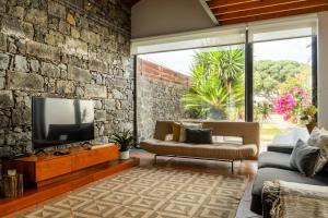 a living room with a tv and a stone wall at Casa da Arvore Chale by Green Vacations in Calhetas