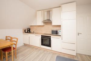 a kitchen with white cabinets and a table and a microwave at Schleiblick App 6 in Rabenkirchen-Faulück