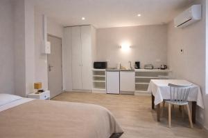 a room with a bed and a table and a kitchen at Hôtel des Thermes in Bourbon-Lancy