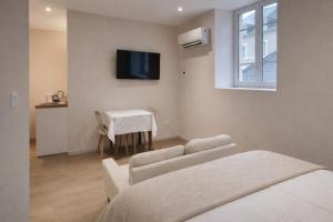 a room with two beds and a table and a television at Hôtel des Thermes in Bourbon-Lancy
