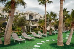 a row of chairs and palm trees in front of a building at Cunda Callisto Hotel & Spa Adult Only 12 in Ayvalık