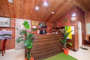 a restaurant with two palm trees in front of a counter at Tulips Resorts - Elkhill in Ooty