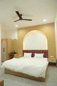 a bedroom with a large bed with a ceiling fan at Hotel Shiv Om in Ujjain