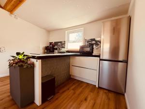 a kitchen with a stainless steel refrigerator and wooden floors at Fabians Ferienhaus - Rurseeloft in Simmerath
