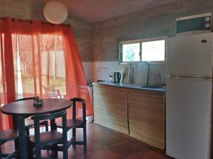 a small kitchen with a table and a refrigerator at Casas Las Coloradas in Piriápolis