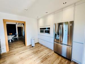 a kitchen with a stainless steel refrigerator and wooden floors at La lisière romantique in Granges-Aumontzey