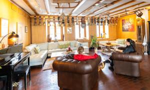 a living room with two people sitting on leather couches at Hôtel Restaurant du Marchairuz in Le Brassus
