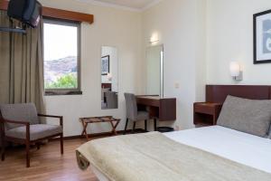a hotel room with a bed and a desk and a window at Flag Hotel Madeira - Ribeira Brava in Ribeira Brava +62 photos