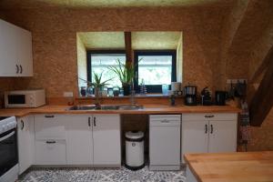 a kitchen with white cabinets and a sink and a window at Plantes et sabots in Barriac-les-Bosquets