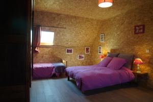a bedroom with two beds with purple sheets and a window at Plantes et sabots in Barriac-les-Bosquets