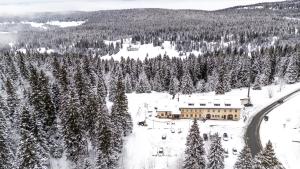 a ski lodge in the middle of a snow covered forest at Hôtel Restaurant du Marchairuz in Le Brassus