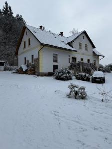 a house with a snow covered yard in front of it at Romantický vejminek pod horami in Kounov