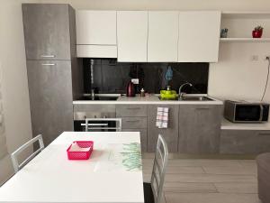 a kitchen with white cabinets and a white table with a pink box at Apartment Orio Volta in Orio al Serio +7 photos