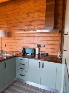 a kitchen with white cabinets and a wooden wall at Sunset Eco Shelter 2 in Ponta do Pargo