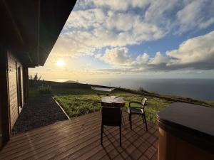 a table and two chairs on a deck with a view of the ocean at Sunset Eco Shelter 3 in Ponta do Pargo