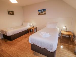 two beds in a small room with two tables at Foyle Cottage in Strabane
