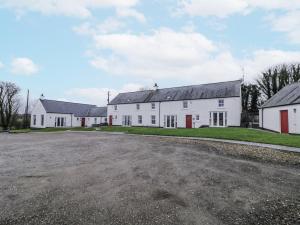 a row of white buildings with a gravel driveway at Foyle Cottage in Strabane