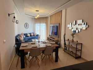 a living room with a table and a blue couch at Beachfront Apartment in Assilah, Private Solarium, 4 Pools, Secure Residence, WiFi, Parking in Asilah