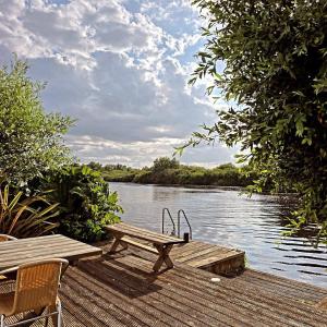 a wooden dock with a picnic table on a lake at Dinky Daze Norfolk Broads in Brundall
