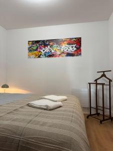 a bed in a bedroom with a painting on the wall at Logement 11 parking gratuit in Poitiers