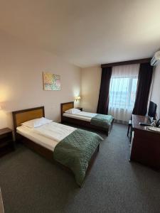 a hotel room with two beds and a desk at Hotel Hanul de la Rascruce in Arad
