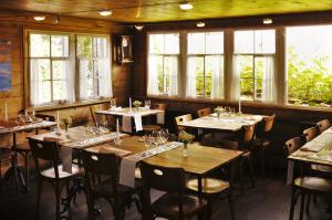 a dining room with tables and chairs and windows at Gasthaus Rössli in Mogelsberg