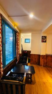 a living room with a table and a large window at Bawli Treehouse Duplex, Jibhi in Jibhi