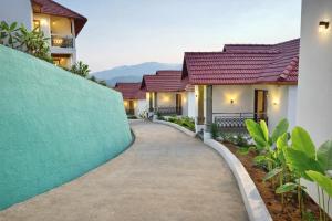 a walkway leading to a house with red roofs at Astralis Resort Coorg in Madikeri