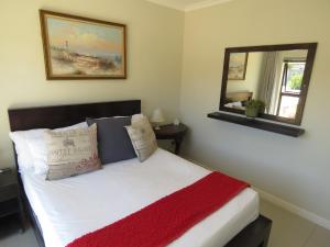 a bedroom with a bed with a red blanket and a mirror at the range in Langebaan