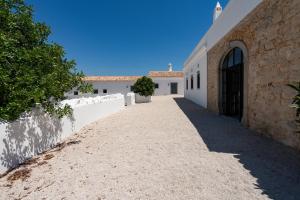 a driveway leading to a white building with a door at Uma Casa Rural in Santa Bárbara de Nexe +31 photos